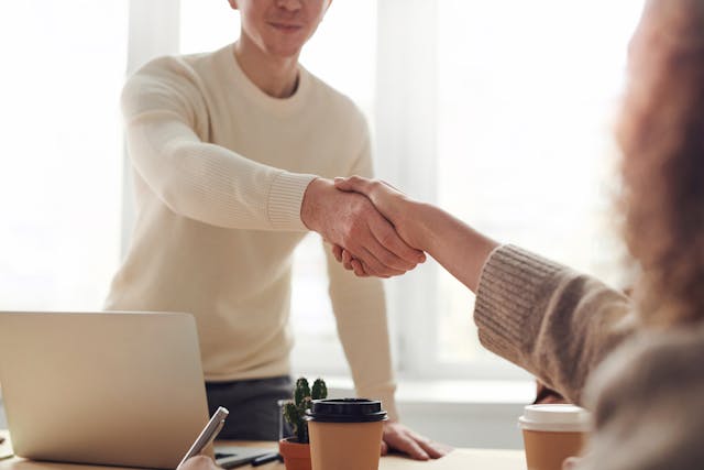 Handshake over a table, bright color scheme an lighting